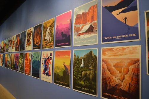 Collection of vintage-style national park travel posters displayed on blue wall including Grand Canyon and Yosemite