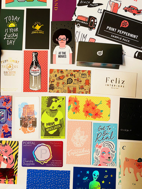 Collection of colorful vintage-style postcards, business cards and graphic design samples arranged on white surface