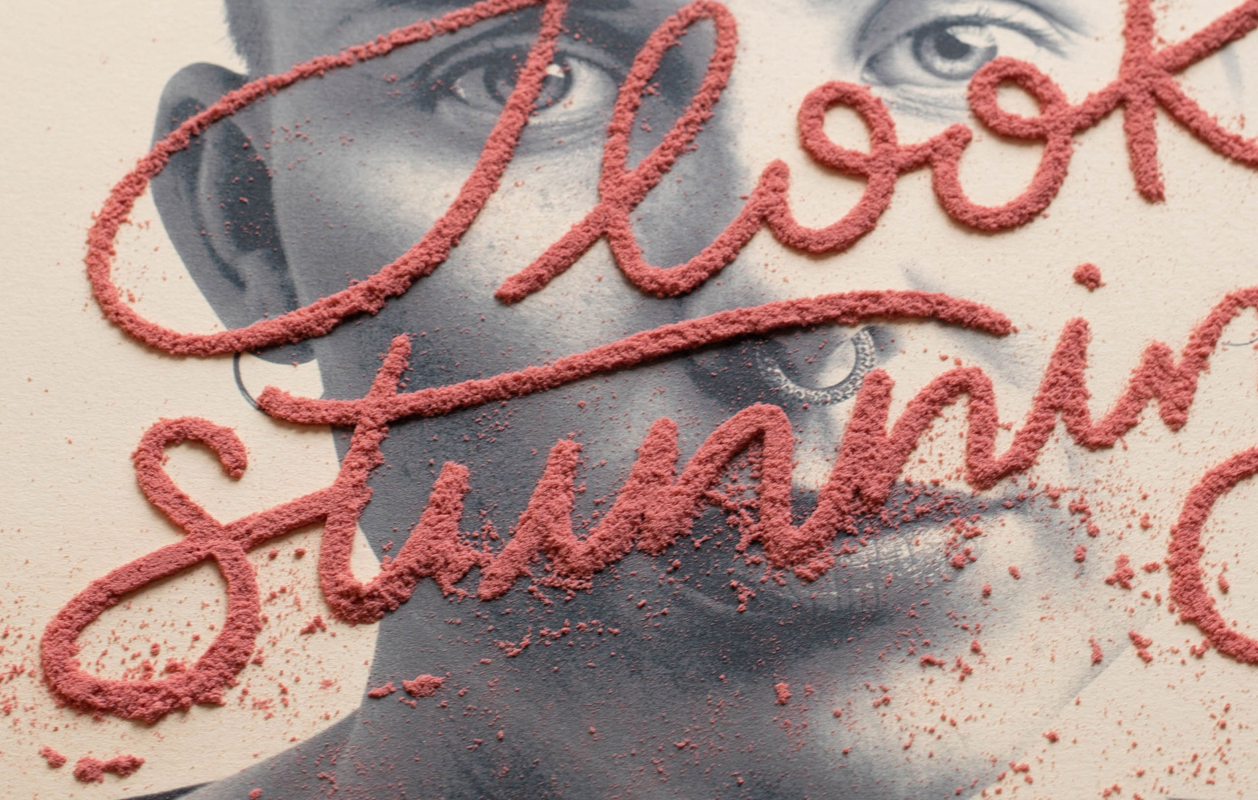 Red sand art spelling Alison Stuart over black and white portrait photo with scattered sand particles