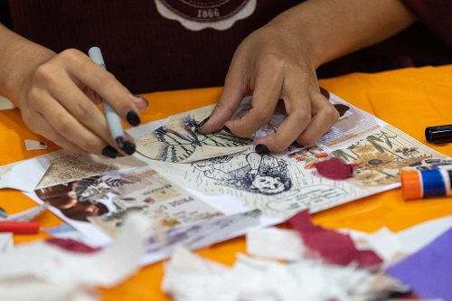 Person creating handmade collage art with vintage images, sketches, and craft supplies on orange workspace table