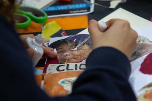 Child cutting out magazine pictures with green scissors for arts and crafts project