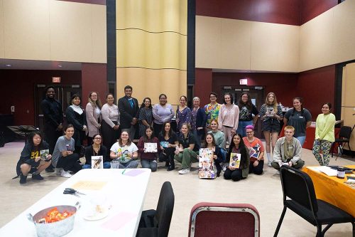 Group of students and teachers posing with artwork at school art class or workshop event in classroom setting