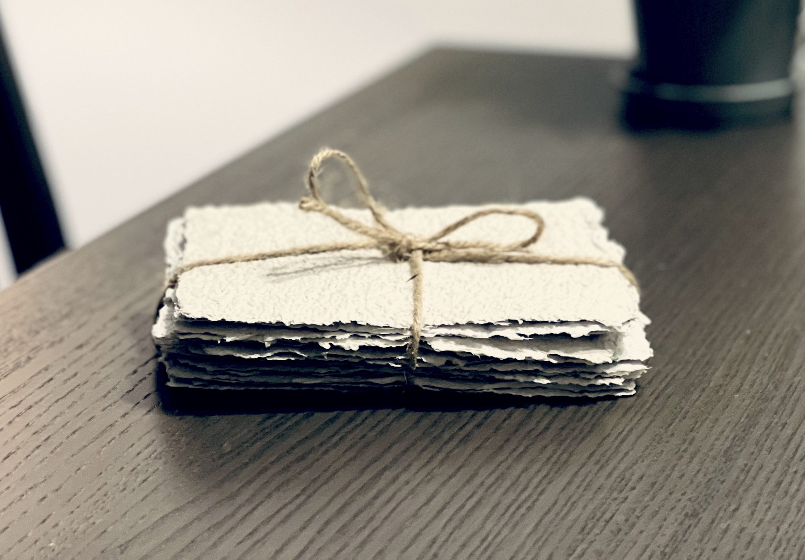 06 Bundle of vintage letters tied with twine string sitting on wooden desk surface